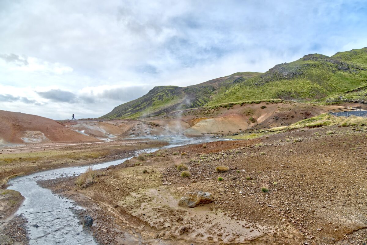 A steaming hot spring on a dry and rocky landscape.
